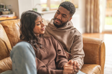 Couple shares a cozy moment on a sofa in a bright living room, enjoying each other's company in a relaxed atmosphere