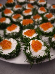 Delicious christmas canapes with red caviar and cream cheese nestled in fresh dill party food for aperitif, New Year's Eve dinner, Christmas or birthday
