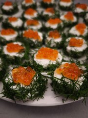 Delicious christmas canapes with red caviar and dill on white plate party food for aperitif, New Year's Eve dinner, Christmas or birthday