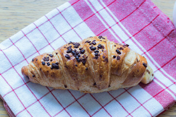 Chocolate croissant with chocolate chip sprinkles on white and red tea towel
