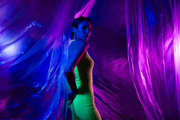 Portrait of lovely model girl posing green dress isolated on neon studio curtain background