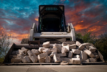 Skid steer loader for construction site with loading bucket filled with bricks.	
