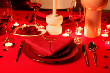 Dining table with setting, burning candles and decor for Valentine's Day celebration in evening