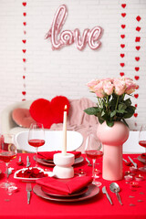 Table setting decorated for Valentine's Day with pink roses and candles at home