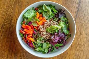 Bowl of quinoa salad with leafy greens and various veggies seen from above highlighting vibrant fresh produce