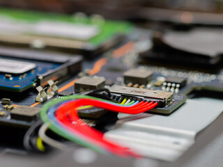 Naklejka premium Laptop battery plug, plus minus clamp. Battery repair shop. Computer technician disassembling mainboard with circuit of laptop repairing.