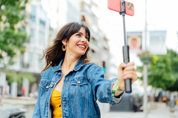 Young woman vlogging with selfie stick and smartphone in the city