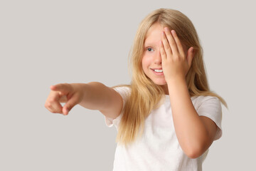 Teenage girl checking her eyesight on light background. Children's Eye Health and Safety Awareness...