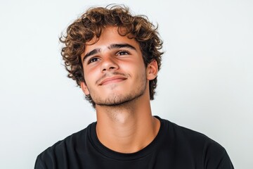 Obraz premium Smiling young Brazilian man gazing sideways against a white backdrop