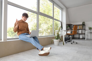 Young man with laptop video chatting in office