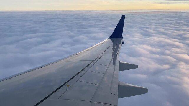 Airplane Wing Above Clouds During Sunrise or Sunset Flight