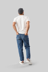 Obraz premium Young man in white t-shirt with cap on light background, back view