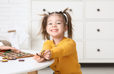 Cute little girl with letter board on table learning alphabet at home