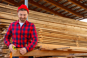 Male carpenter measuring wooden plank at sawmill