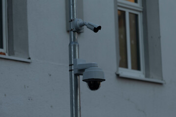Surveillance cameras are securely mounted high at outdoor area. Security, monitoring, and the integration of technology within urban and natural environments. CCTV camera at dark evening.