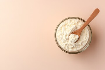 Aerial shot of collagen powder in a bowl with a spoon on a beige background emphasizing a healthy lifestyle theme