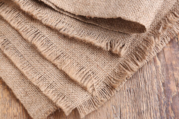 Pieces of burlap fabric on wooden background