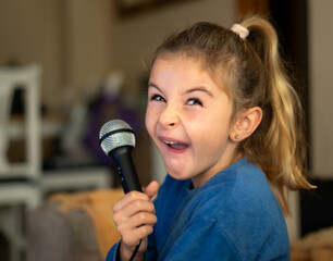 girl makes a funny expression while singing with karaoke