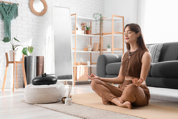 Beautiful young woman with aroma sticks meditating at home