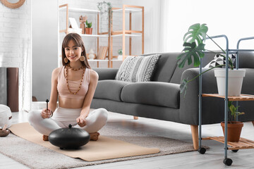 Meditating young woman playing glucophone at home