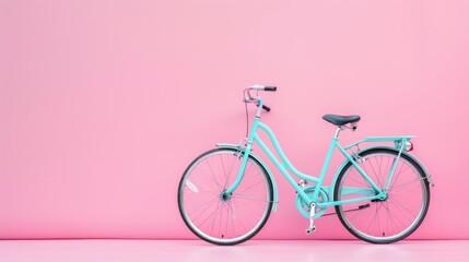Teal bicycle against pink background.