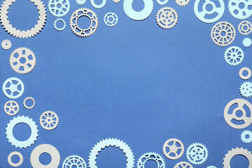 Frame made of different paper gears on blue background