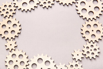 Frame made of wooden gears on grey background