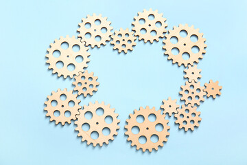 Frame made of wooden gears on light blue background