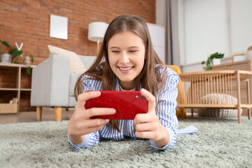 Smiling young woman using mobile phone on carpet at home