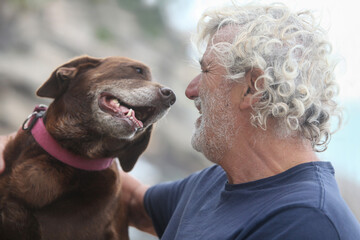 closeup portrait of cheerful senior man with his dog in the park  bonding