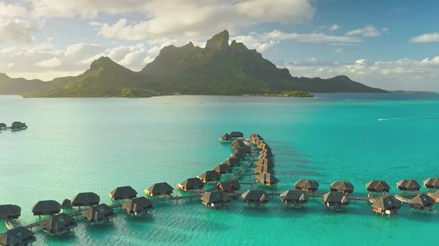 Aerial view of amazing overwater bungalows in Bora Bora, with mount Otemanu in the background, creating a tropical paradise scene. Wild travel destination, remote nature paradise, exotic summer view