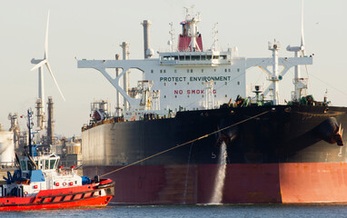 Aerial view of a tugboat and a large oil tanker in the port of Rotterdam
