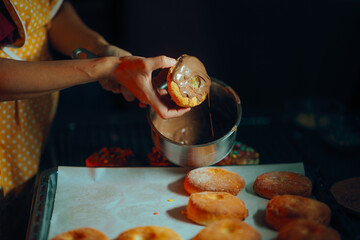 Housewife Glazing Donuts at Home with Liquid Chocolate. Skillful home cook preparing round frosted...