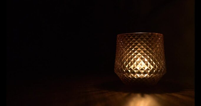 Candle flame flickering in the glasswork illuminating the darkness, 4K, 60 fps