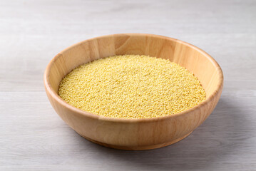 Organic yellow millet grain in wooden bowl on white table, Healthy food ingredient