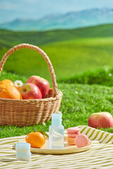 Picnic on green hill photograph from front view. A blue unbranded bottle displayed on a dish with some picnic foods. Mockup for cosmetic advertisement