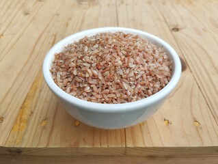 Red rice in bowl on wooden table 