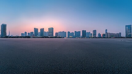 Empty asphalt road with modern city skyline at dawn.