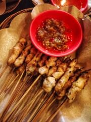 Taichan satay or taichan satay, made from chicken, served on a rattan plate with sauce, soy sauce and lime. this food is like yakitori
