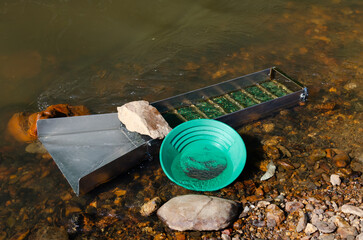 Gold panning and mining in riverbed. prospecting for gold using sluice box and gold pan. Gold...