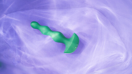 Green anal beads in highlights on purple background. 