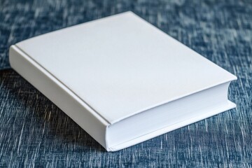 Fototapeta premium Blank white book on blue fabric. Perfect for book cover designs, mockups, or publishing projects.