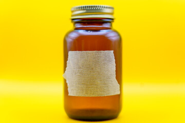 Amber glass jar with blank label on yellow background