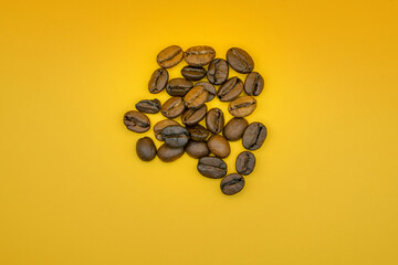 Scattered roasted coffee beans on yellow background