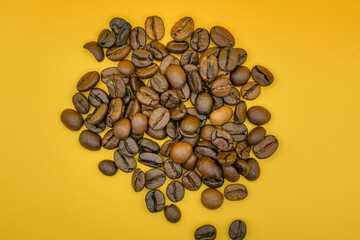 Heap of roasted coffee beans on yellow background