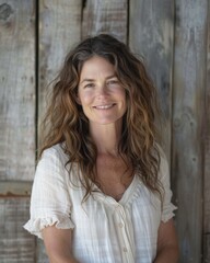 Fototapeta premium Portrait of a Smiling Woman with Long Brown Hair Against a Rustic Wooden Background