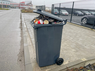 A container full of garbage, garbage hanging over the edges