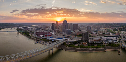 Obraz premium Highway traffic on bridge in Cincinnati, Ohio with brightly illuminated high skyscraper buildings in downtown district. American city with business financial district at sunset