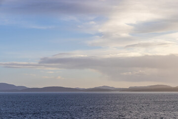 Tranquil Coastal View of Ocean and Mountains Under a Cloudy Sky