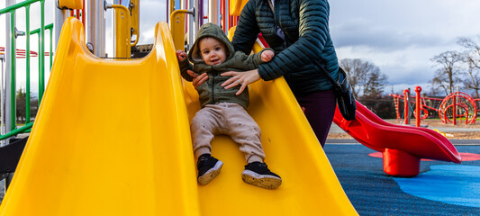 Parent and Child Enjoying Park Slide on a Sunny Day